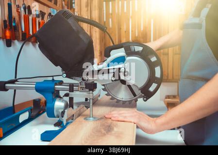 Carpenter using miter saw while working on flooring panels Stock Photo