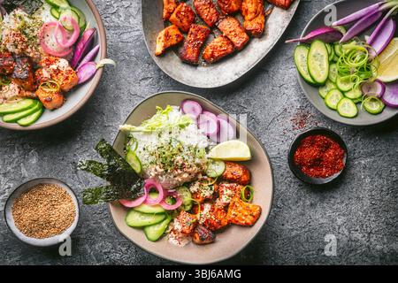 An overhead shot with a custom gray stone textured surface with two beautiful ceramic bowls filled with rice, fresh vegetables, seaweed, and crispy, g Stock Photo