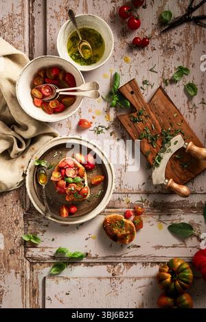 preparation of bruschetta with tomatoes and herbs with olive oil on wood Stock Photo