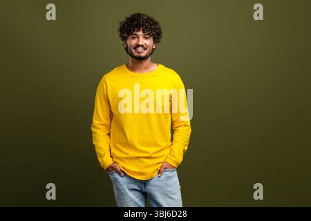 Portrait of a young man wearing a vibrant yellow shirt against a stylish khaki background, showcasing casual fashion Stock Photo