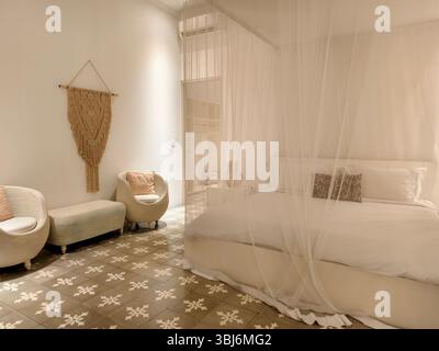 A tranquil bedroom decorated in a soft boho-chic style, featuring a canopy bed and macrame wall art Stock Photo