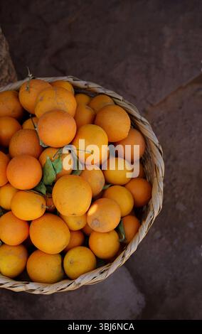 Basket of Fresh Oranges in Moroccan market, earthy brown background with copy space Stock Photo