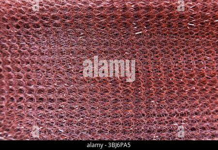 The texture of a soft copper mesh twisted into a roll. Stock Photo