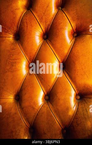 The texture of the leather sofa upholstery, brown, with rivets. Stock Photo