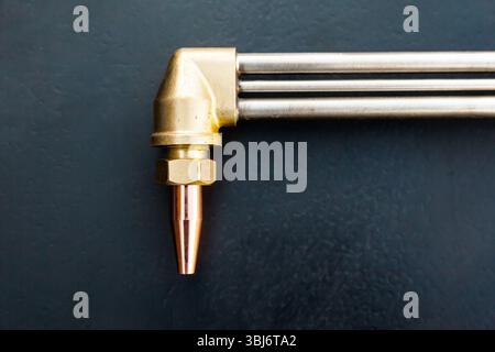 Gas cutter on a black background. New bronze torch with copper tip. Stock Photo