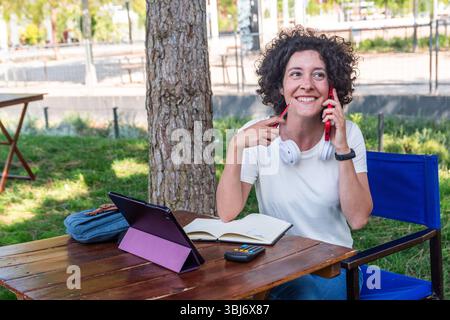 Digital nomad working outdoors and talking on phone Stock Photo