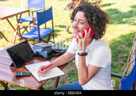Digital nomad working remotely outdoors and talking on phone Stock Photo