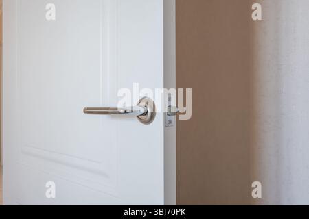 modern door handle on white wooden door in interior. Knob close-up elements. Door handle, fittings for interior design Stock Photo