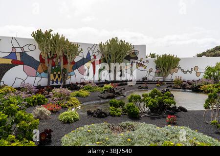 A vibrant garden at the Cesar Manrique Foundation in Lanzarote features a unique wall mosaic and diverse plant life. Stock Photo