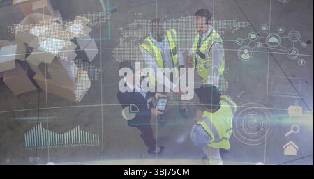Collaborating warehouse team in neon vests analyzing map overlay on tablet inside distribution hub Stock Photo