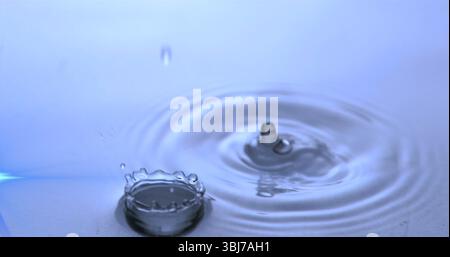 Capturing droplet hitting water in studio, forming crown-shaped and column splashes with ripples Stock Photo