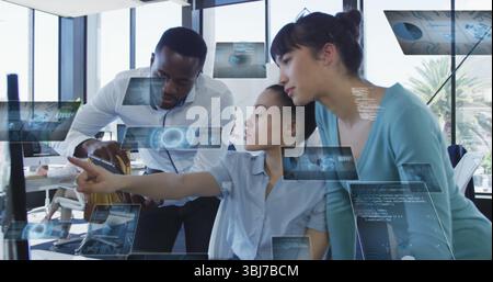 Three professionals analyzing data visuals on desktop in modern office, with holographic charts Stock Photo