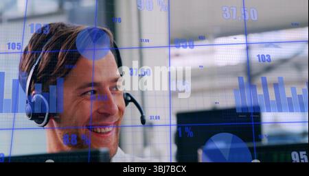 Smiling adult man wearing headset analyzing data charts at office desk, with computer Stock Photo