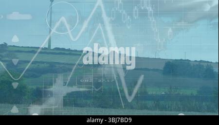 Displaying white wind turbine standing over hedgerows and rolling fields, overlaying line charts Stock Photo