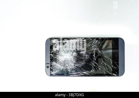 Close-up of a gray cell phone's fractured screen on a white background Stock Photo