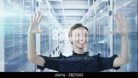 Engineer in ruffled top using holographic display in data center aisle, with server racks Stock Photo