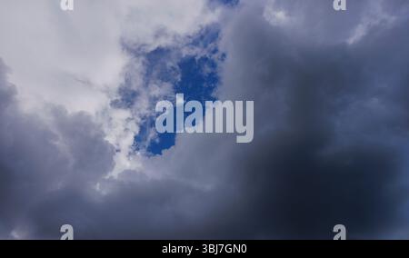 Glimpse of blue sky behind dark gray clouds, Finland Stock Photo