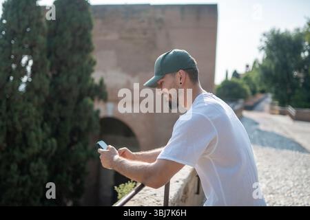 Smiling tourist using a smartphone and writing. Stock Photo
