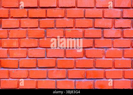 Background of uniform brick wall. Consistent pattern of the bricks creates a strong visual texture. Orange brick wall, a classic architectural element Stock Photo