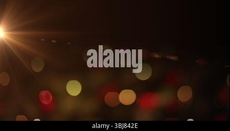 Shimmering colored light orbs shifting across dark backdrop at nighttime, lens flare Stock Photo