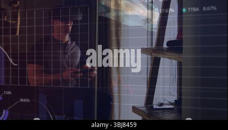 Man wearing VR headset and holding controllers exploring virtual financial charts in home office Stock Photo