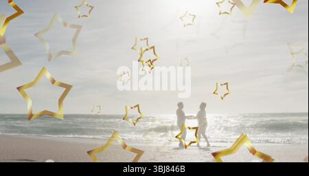 Dancing senior couple holding hands on sandy shoreline at ocean edge, with golden star outlines Stock Photo