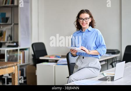 Young happy business woman holding tablet posing in office, portrait. Stock Photo