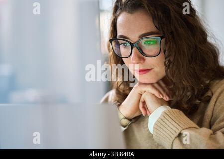 Young professional woman using laptop watching online webinar at work. Stock Photo