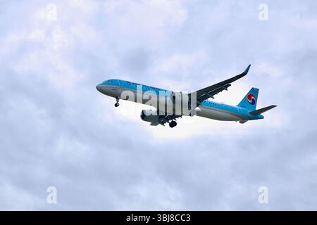 Incheon, South Korea - May 19th 2025: A Korean Air passenger jet lowers its landing gear as it descends through cloudy skies, flying over the Ara Wate Stock Photo