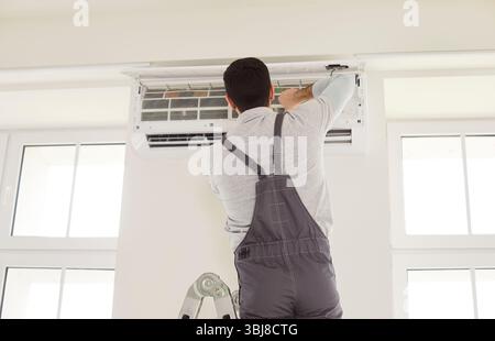 Worker man installing or attaching the air conditioning unit, repair blowing warm, room temperature Stock Photo
