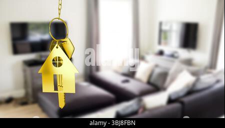 Suspending golden house-shaped key ring on gold-tone chain in living room, with metal key Stock Photo