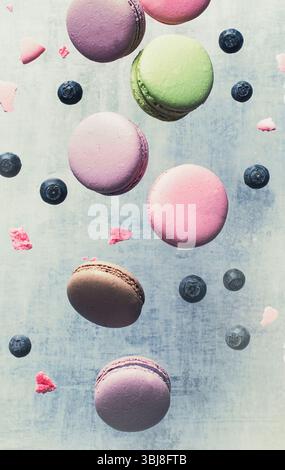French sweet macaroons flying in motion on a blue background. Stock Photo