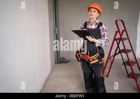 Building worker Wearing Hardhat With Clipboard standing in New Property. Repair and renovation apartment Stock Photo