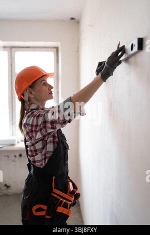 Builder checking wall using spirit level, during building construction or home renovation Stock Photo
