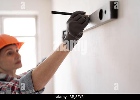 home improvement and repair concept. Construction, builder and contractor with level measuring. handyman in hardhat holding spirit level Stock Photo