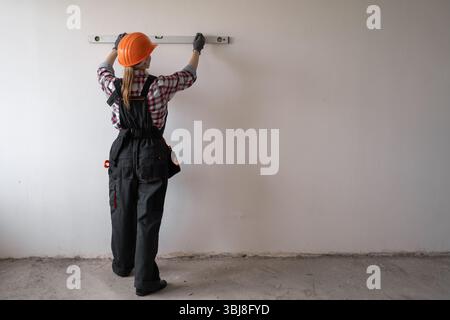 home improvement and repair concept. Construction, builder and contractor with level measuring. handyman in hardhat holding spirit level. Stock Photo