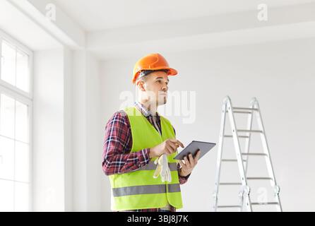Worker Planning Renovation Using Tablet Pc And Blueprint At Home Stock Photo