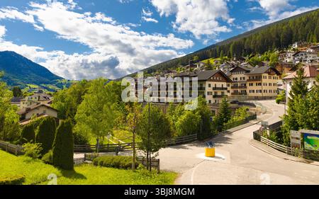 An aerial view of Ortisei, a picturesque Alpine village in the Dolomites, featuring traditional buildings nestled on a hillside with lush green trees Stock Photo