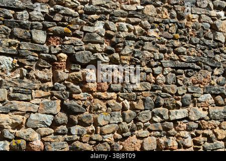 A weathered stone wall showcases a mix of colors and textures Stock Photo