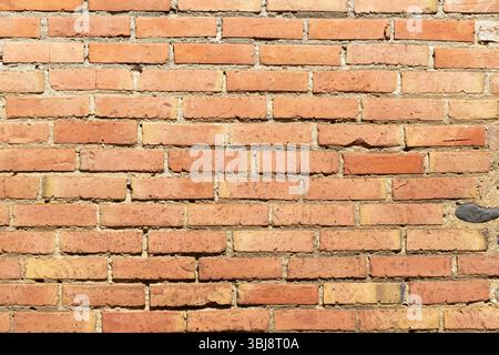 A weathered brick wall showcases a variety of brown and orange hues, highlighting the texture and unique patterns formed over time. Stock Photo