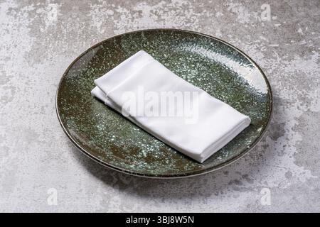 Elegant green ceramic plate with folded white napkin on stone Stock Photo