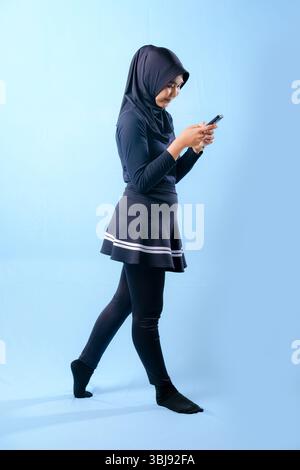 A woman wearing a black skirt and black pants is holding a cell phone. She is smiling and she is happy Stock Photo