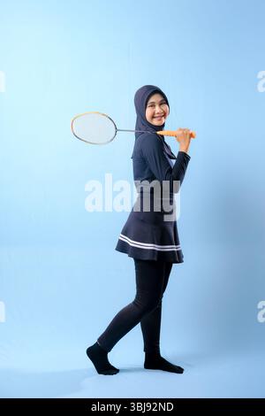 A woman in a black skirt and black pants holding a badminton racket. She is smiling and she is happy Stock Photo