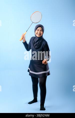 A woman in a black skirt and black pants holding a badminton racket. She is smiling and she is happy Stock Photo