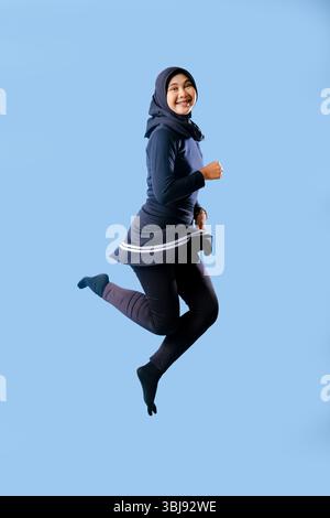 A woman in a black skirt is jumping in the air. She is smiling and she is happy Stock Photo