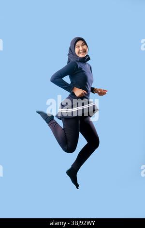 A woman in a black skirt is jumping in the air. She is smiling and she is happy Stock Photo