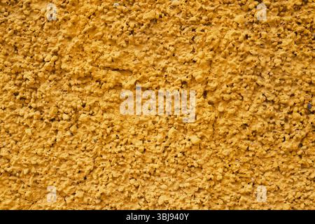 Close-up of a textured yellow stucco surface showing uneven, bumpy details and natural imperfections. Stock Photo