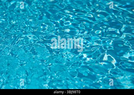 Shallow depth of field details with clear blue and transparent water in a swimming pool during a sunny warm day Stock Photo