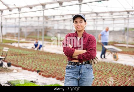 Young woman worker posing joyfully in greenhouse Stock Photo