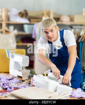 Professional young repairman master repairing sewing machine in fashionable sewing studio or sewing workshop Stock Photo